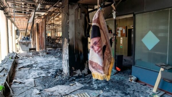 An image of Ayatollah Ali Khamenei dangles in a building damaged by Israeli strikes