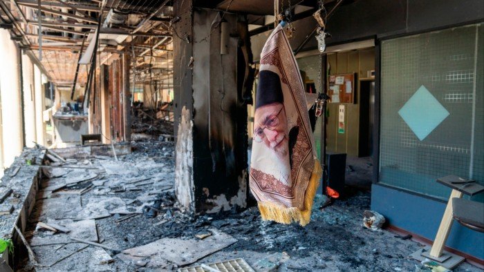 An image of Ayatollah Ali Khamenei dangles in a building damaged by Israeli strikes